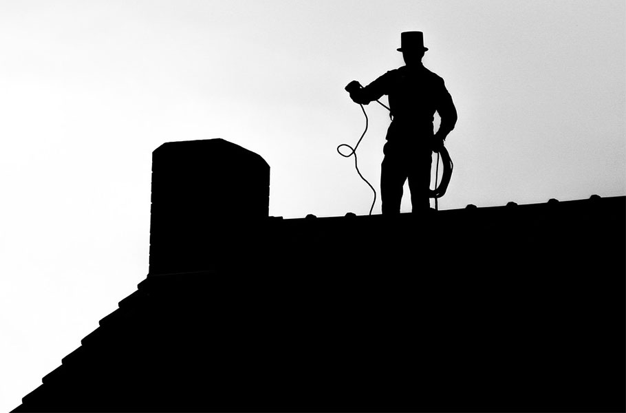 chimney sweep on roof preparing to service chimney