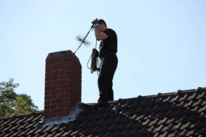 chimney sweep on roof next to chimney