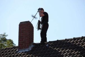 Schedule an Annual Inspection - Middlesex County MA - Chim Chimney chimney sweep on roof next to chimney